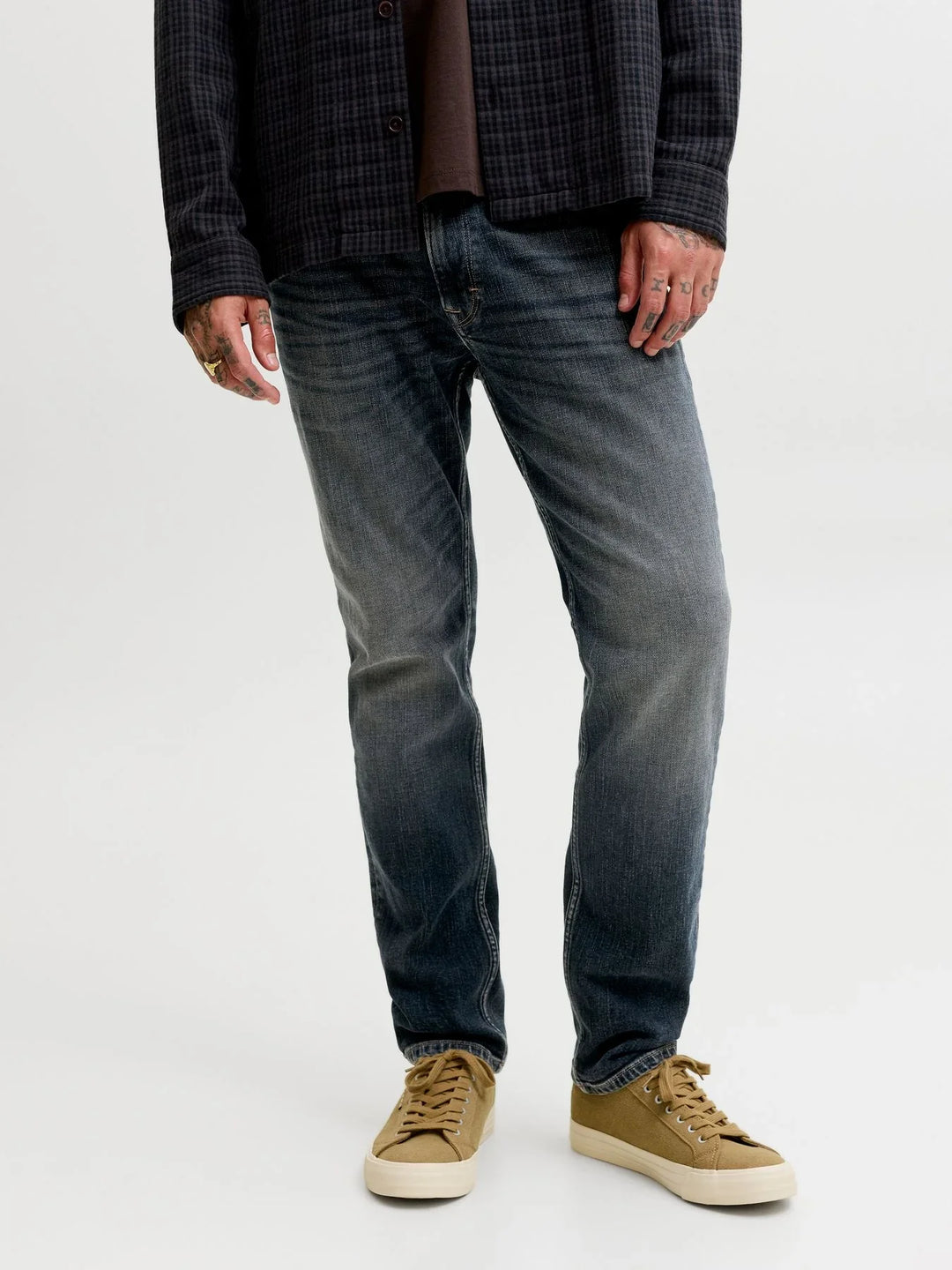 Dunkelblaue Herrenjeans im Straight Fit mit dezenter Used-Waschung. Kombiniert mit beigefarbenen Sneakern für einen lässigen Alltagslook.