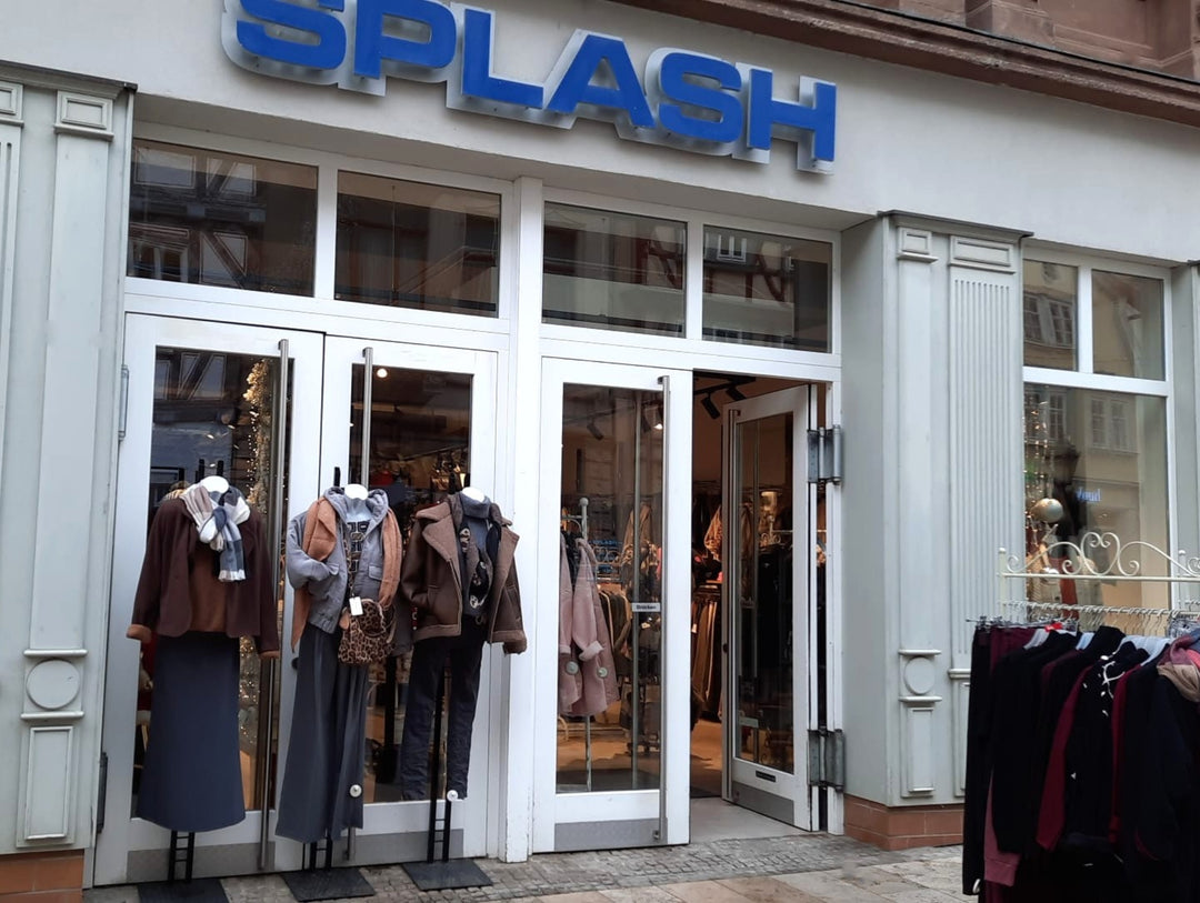 Vorderseite des Shops „SPLASH“ mit weißer Fassade und Doppeltür