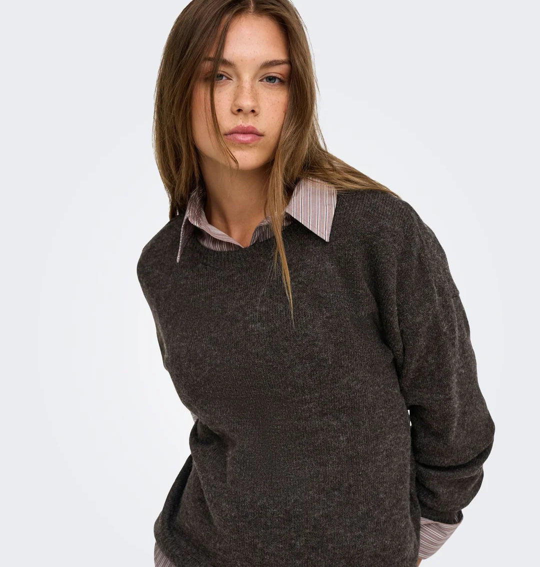Damen-Strickpullover in Dunkelbraun mit Rundhalsausschnitt, lässig über einer gestreiften Bluse und zu heller Jeans kombiniert.